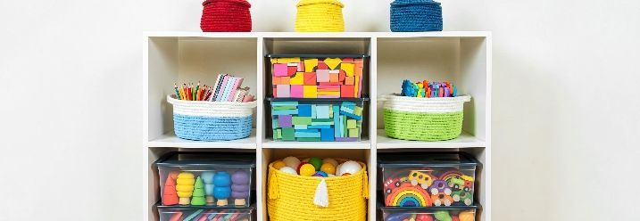 Weißes Regal mit bunten Spielzeugkörben